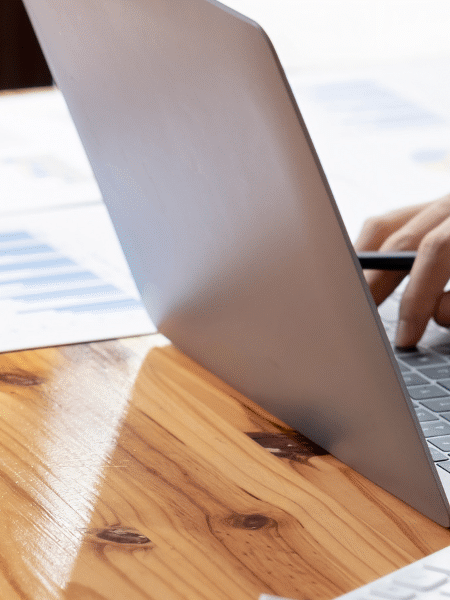 A blog feature image of a male accountant in his office, manually entering data into his laptop, with scattered papers on his desk. This image illustrates the necessity of a Paperless Accounts Payable process