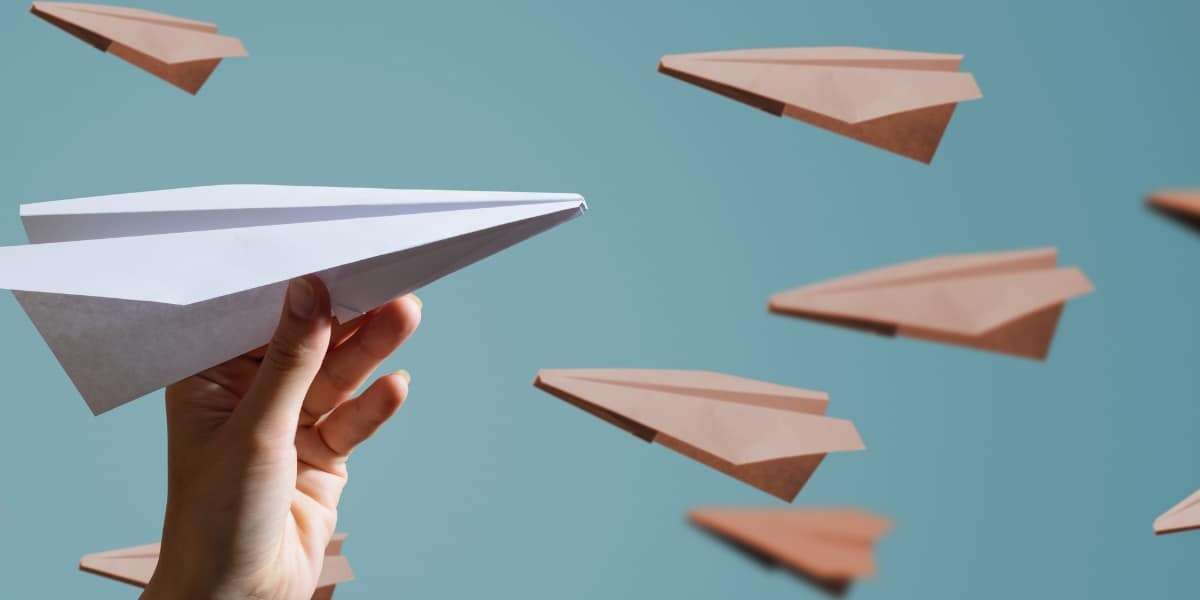 Conceptual image of paper planes one being help by a hand in the foreground, to represent business manual document processing and the need for a data capture solution for greater efficiency.