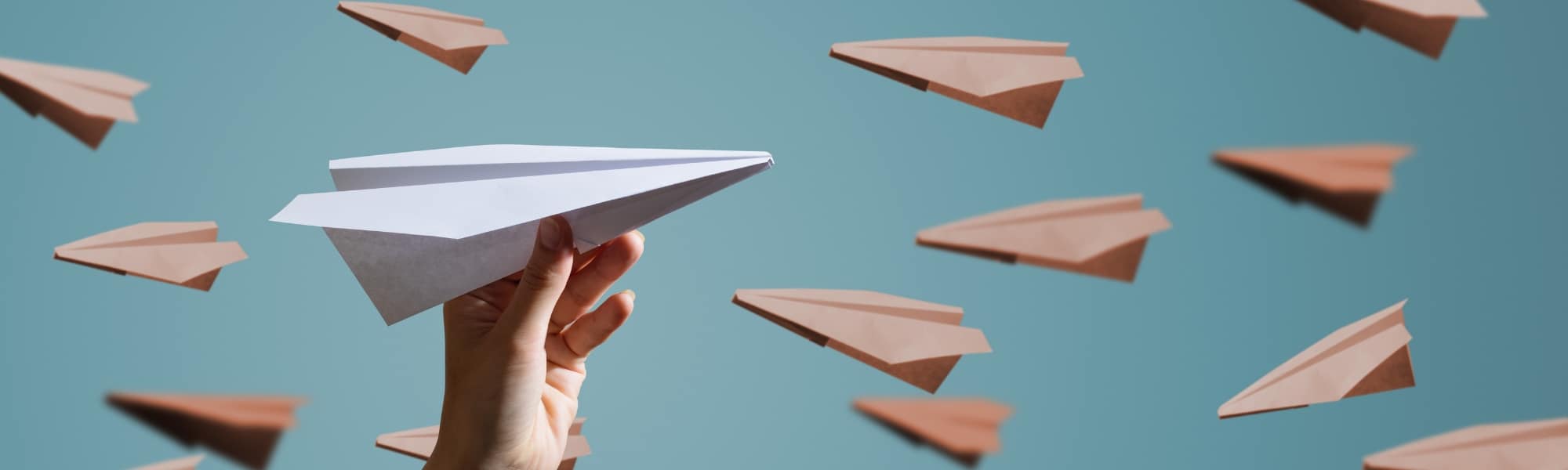 Conceptual image of paper planes one being help by a hand in the foreground, to represent business manual document processing and the need for a data capture solution for greater efficiency.
