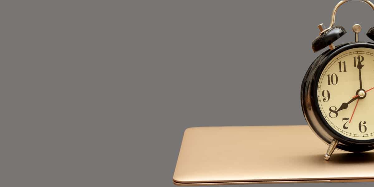 A cutout image of an alarm clock on top of a closed laptop, with a grey background colour. This shows how inefficiency in the finance department can be tackled with Automated accounts payable invoice processing