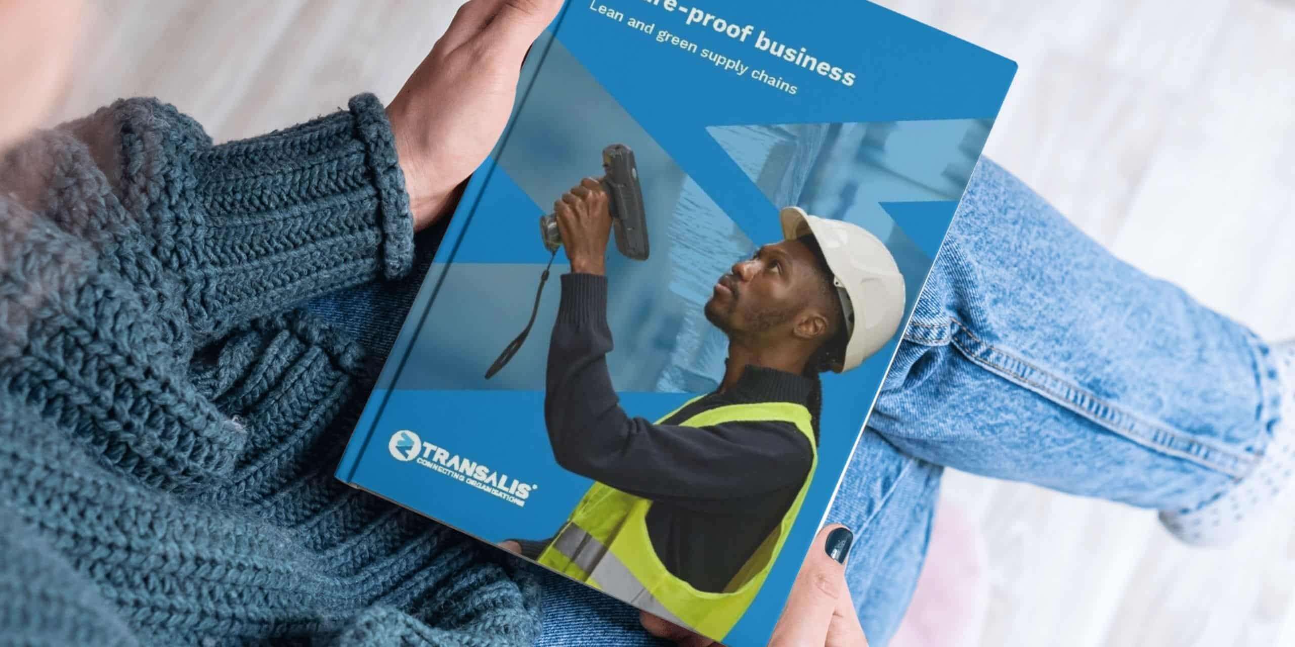 Mockup image of Transalis whitepaper report titled 'Free Report: Build a future-proof business with lean, green supply chain strategies'. Closeup image looking over a woman's shoulder to see her holding the report, looking at the front cover with image of a male warehouse stock manager with a barcode scanner and overlay of Transalis icon logo in blue.