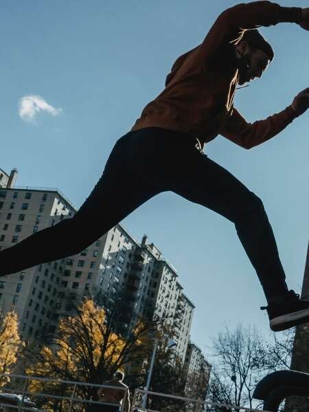 Male parkour runner leaps between buildings in an industrial business complex. Representing a blog post by Transalis, titled: how to achieve business agility