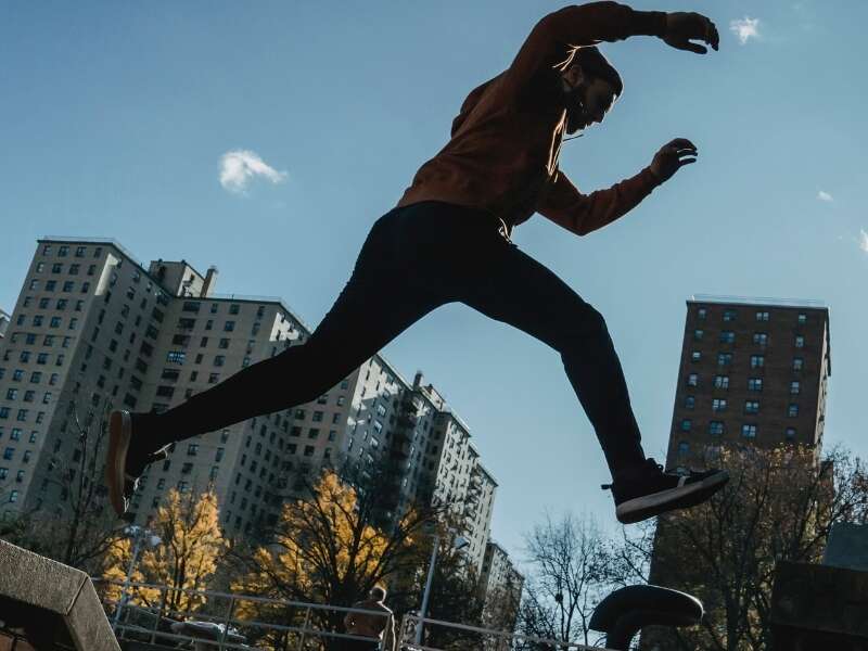 Male parkour runner leaps between buildings in an industrial business complex. Representing a blog post by Transalis, titled: how to achieve business agility