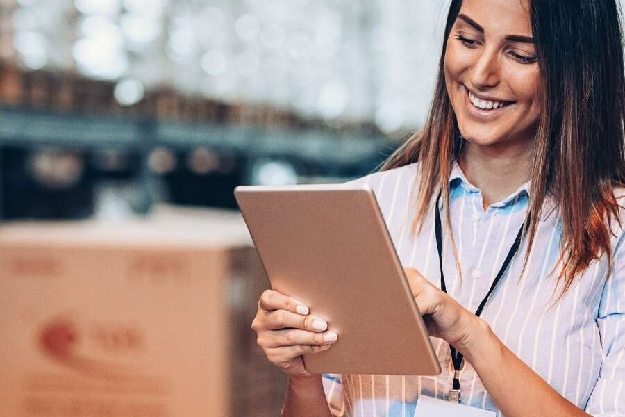 Stock photo of female warehouse manager with a tablet reviewing inventory levels. Representing blog post titled 