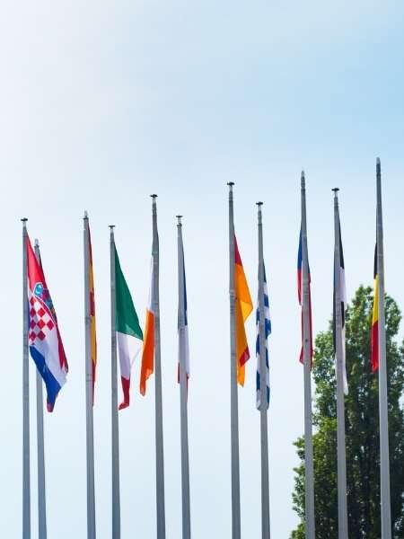 Photo of the row of national flags outside the European Parliament building. Representing a Transalis blog post titled: EU VAT Reporting and eInvoicing Compliance: What You Need to Know