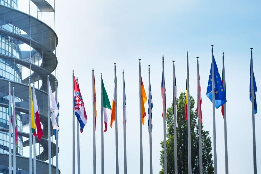 Photo of the row of national flags outside the European Parliament building. Representing a Transalis blog post titled: EU VAT Reporting and eInvoicing Compliance: What You Need to Know