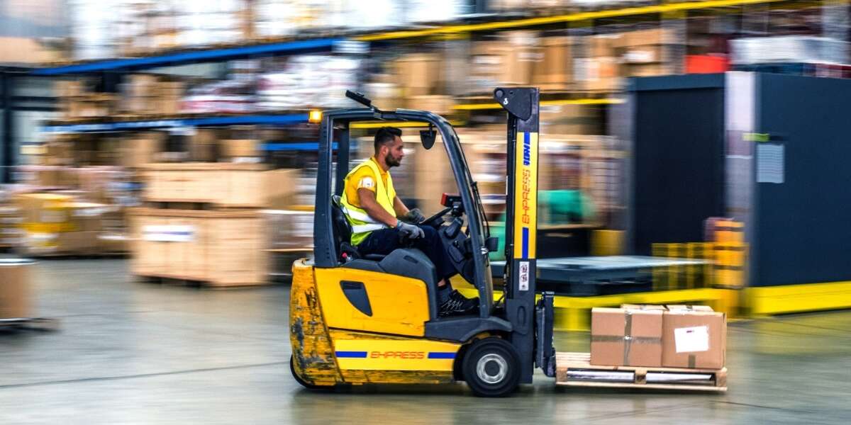Warehouse worker in high visibility jacket operating a forklift. Surroundings of the warehouse are blurred, implying the forklift is in fast forward-motion. Representing blog titled: The real EDI challenges businesses face with traditional systems