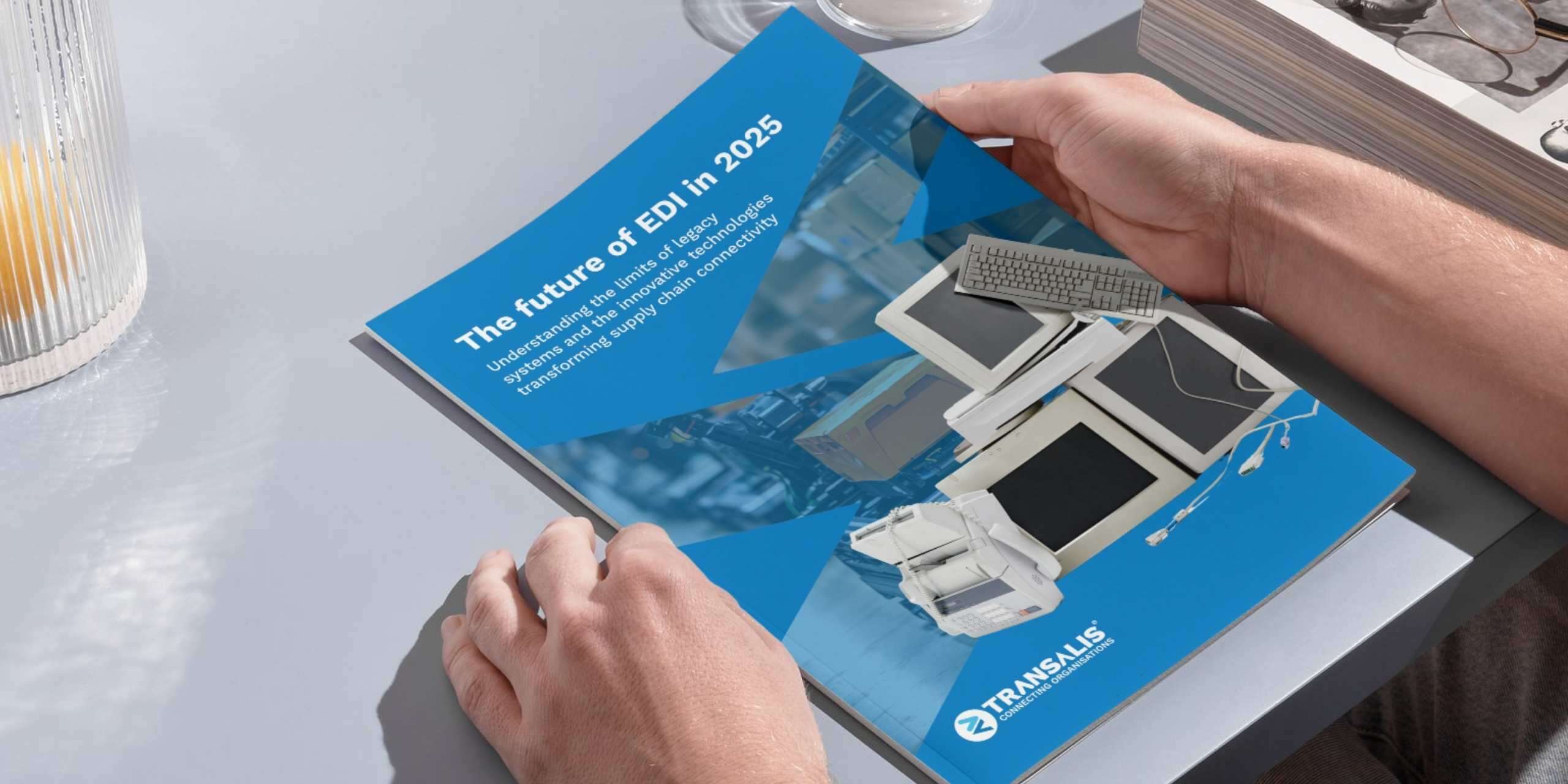 Mockup image of someone holding a booklet of the Future of EDI in 2025 report by Transalis