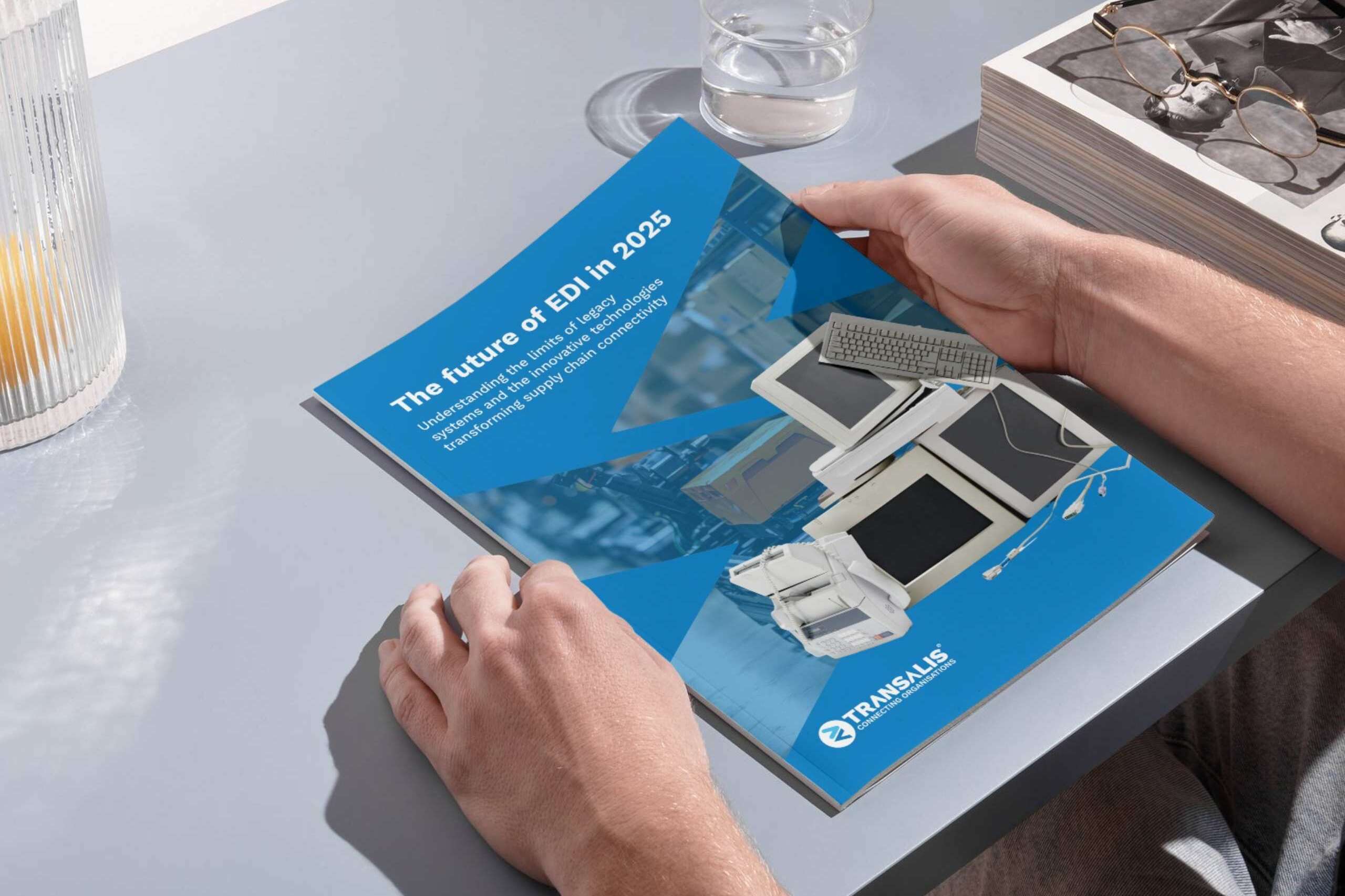 Mockup image of someone holding a booklet of the Future of EDI in 2025 report by Transalis