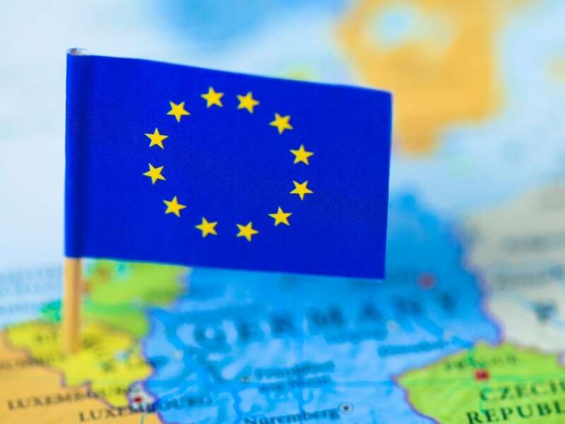 Out of focus map of the continent of Europe in full colour. Mini European flag of stars on cocktail stick in focus and pinned to the location of Brussels in Belgium. Representing the header image of a blog post by Transalis, titled: eInvoicing in Europe: Upcoming deadlines in 2026